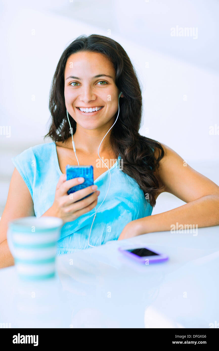 Porträt der lächelnde Frau anhören von MP3-Player am Tisch Stockfoto