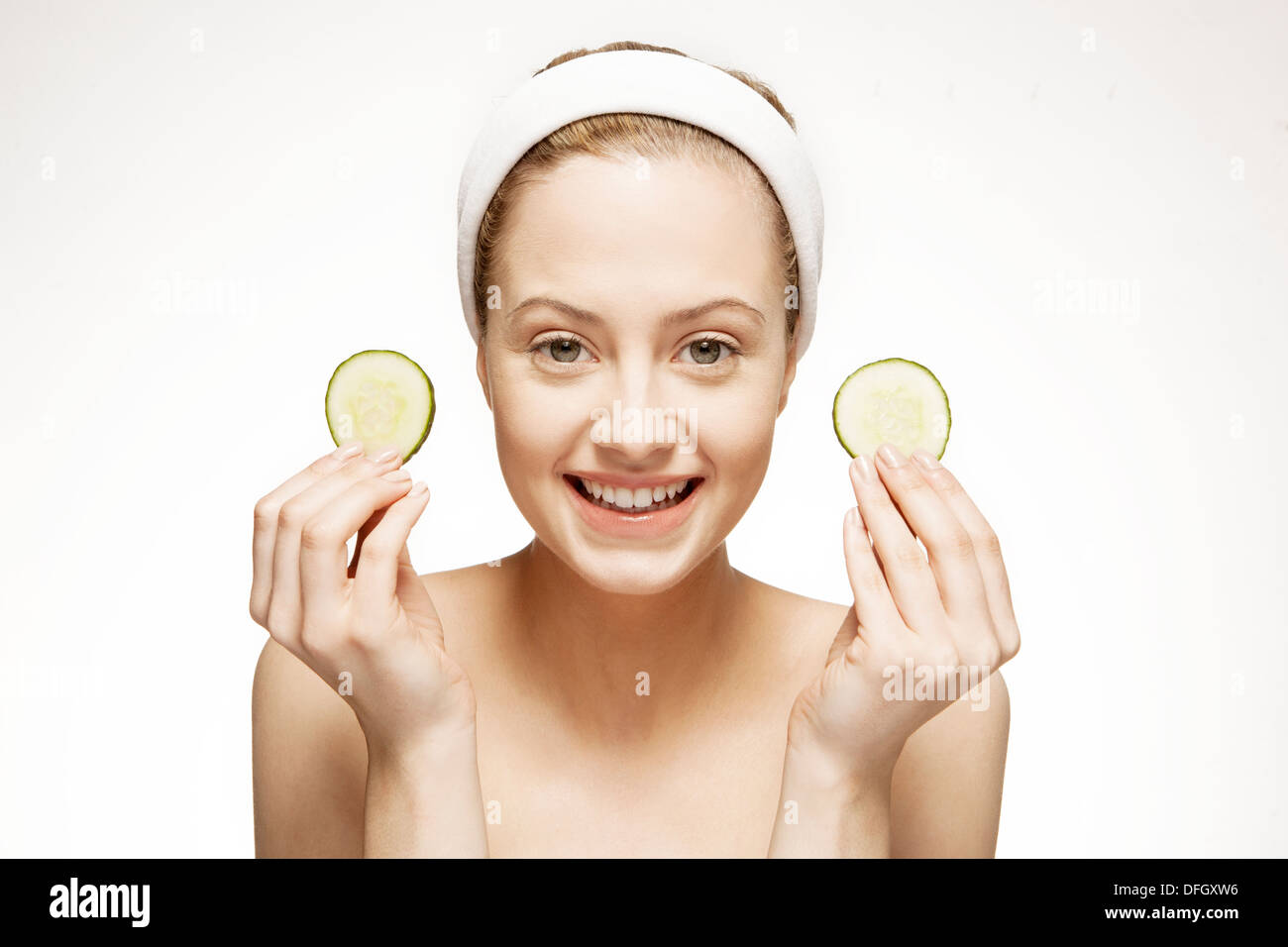 Lächelnde Frau mit Gurkenscheiben Stockfoto