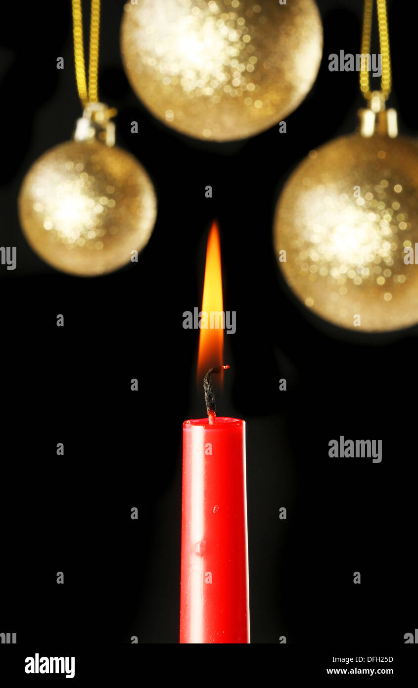 Thema Weihnachten, brennende rote Kerze vor dem Hintergrund der goldenen Kugeln in soft-Fokus Stockfoto