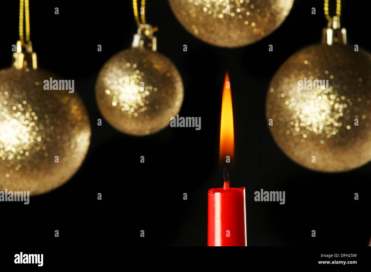 Thema Weihnachten, brennende rote Kerze vor dem Hintergrund der goldenen Kugeln in soft-Fokus Stockfoto