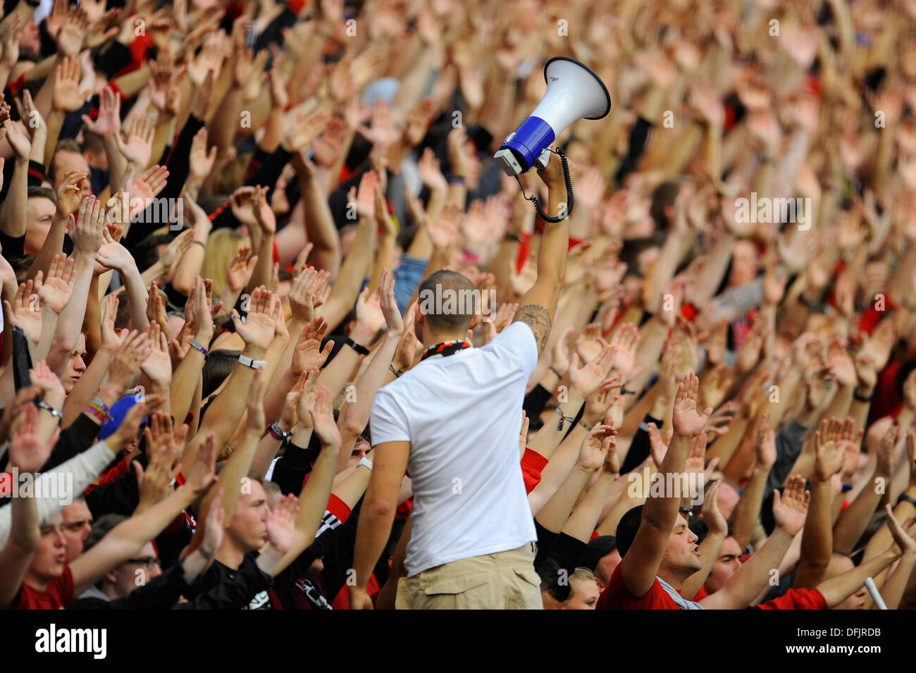 Anhänger des Fußball-Bundesligisten Bayer Leverkusen erheben ihre Hände im Support, angeführt von ihrem Anführer hält ein Megaphon Stockfoto