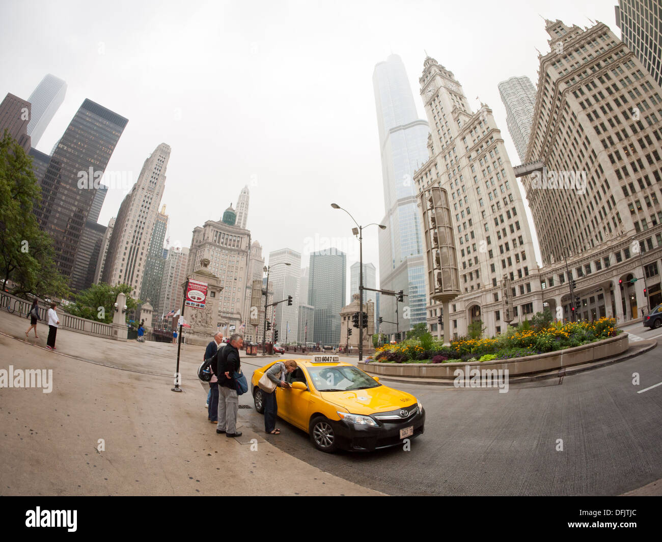 Ein Fischauge Blick auf drei Menschen fangen ein Taxi an der North Michigan Avenue in Chicago, Illinois, an einem bewölkten, trüben Tag. Stockfoto