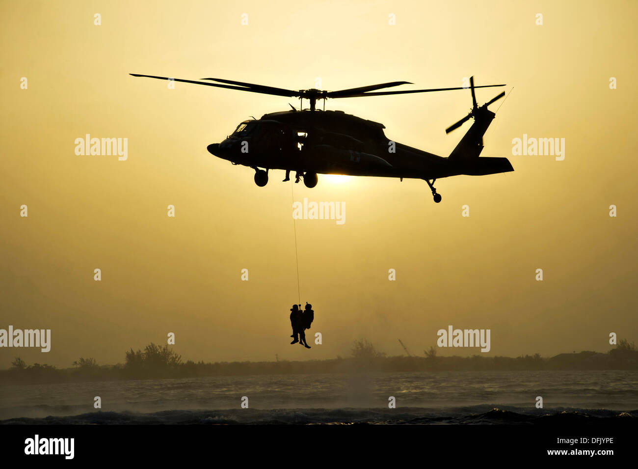 Ein uns Armee UH-60 Black Hawk Hubschrauber hisst Green Berets von 7th Special Forces Group Silhouette gegen die untergehende Sonne 25. Juli 2013 vor der Küste von Utila, Honduras. Stockfoto