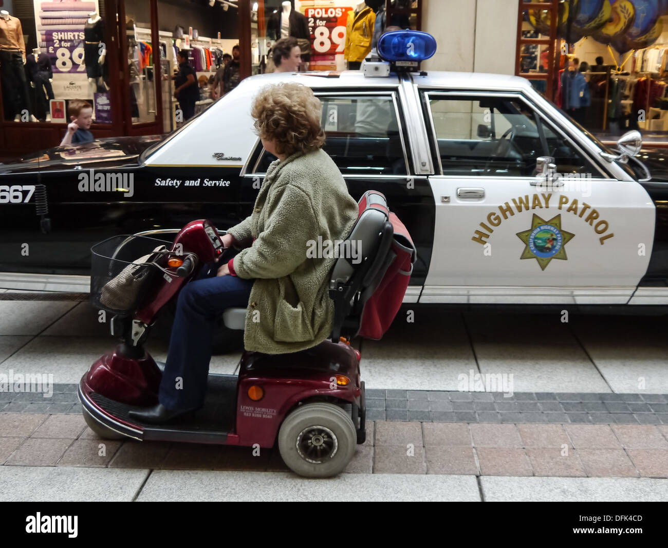 Eine senior Lady in eine mobile Mobilität fährt vorbei an einem Polizeiauto California Highway Patrol Stockfoto