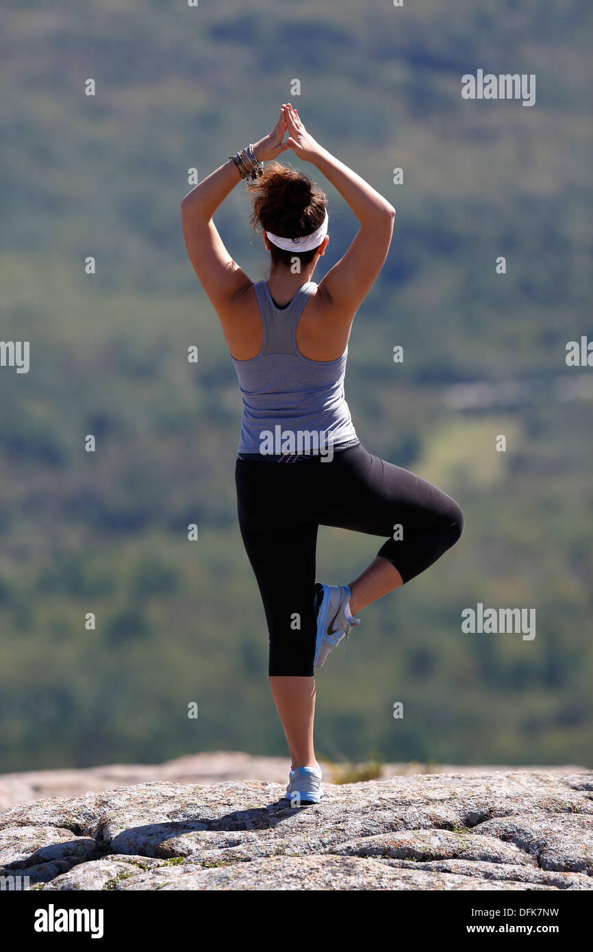 Frau in Yogaposition auf dem Gipfel des Cadillac Mountain, Acadia National Park, Maine, USA Stockfoto
