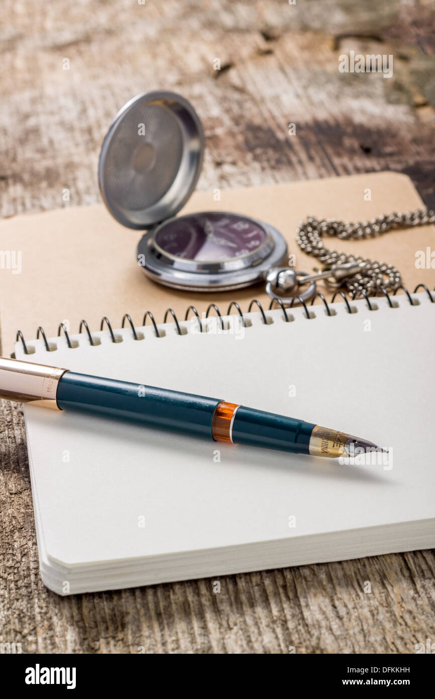 Goldener Kugelschreiber mit Taschenuhr an weiße notebook Stockfoto