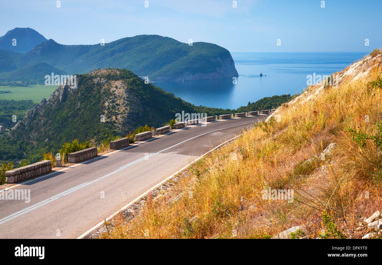 Sommer-Bergstraße mit blauem Himmel und Meer auf einem Hintergrund. Adria, Montenegro Stockfoto