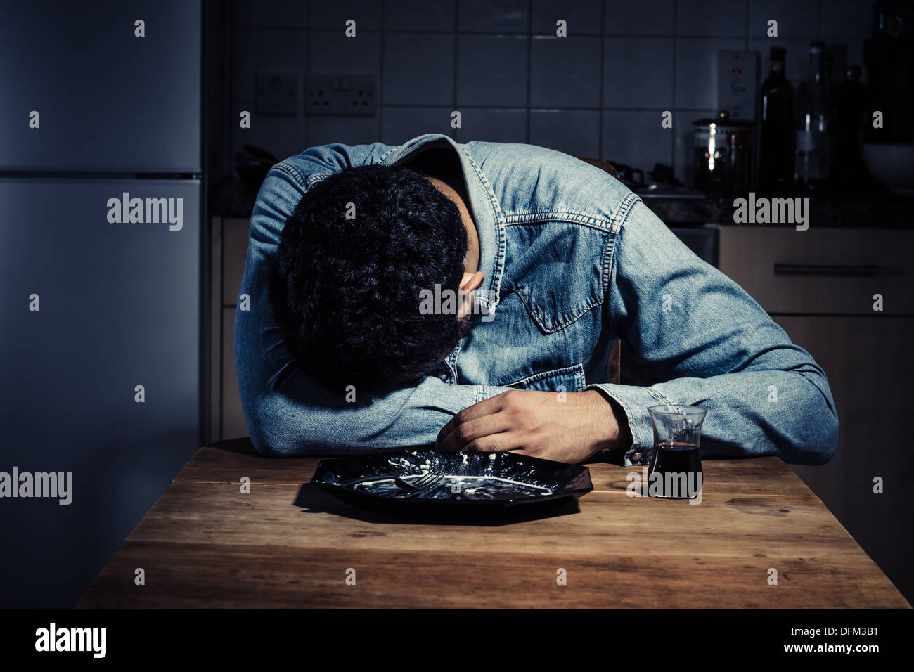Trauriger junger Mann beim Abendessen zu Hause Stockfoto