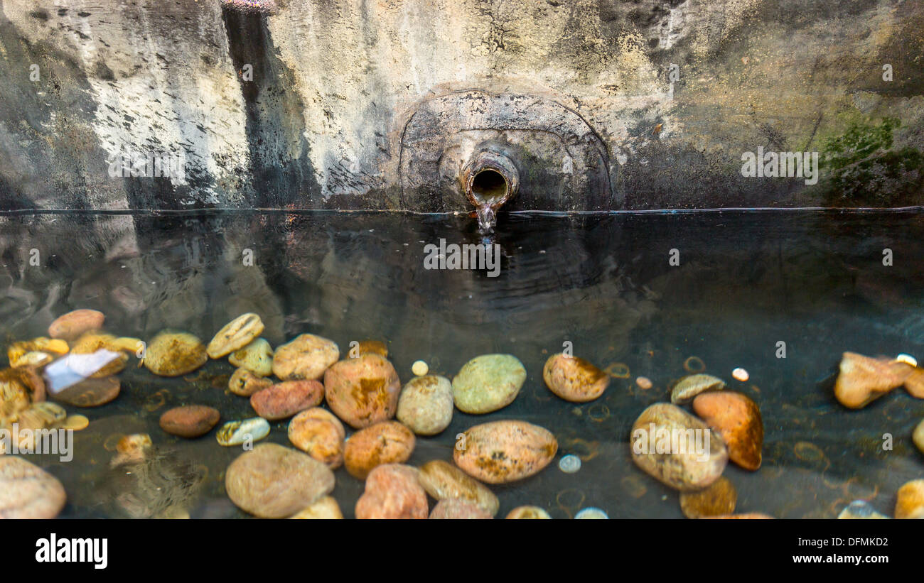 Wasser fließt aus einem alten verrosteten Rohr in einem Teich Stockfoto
