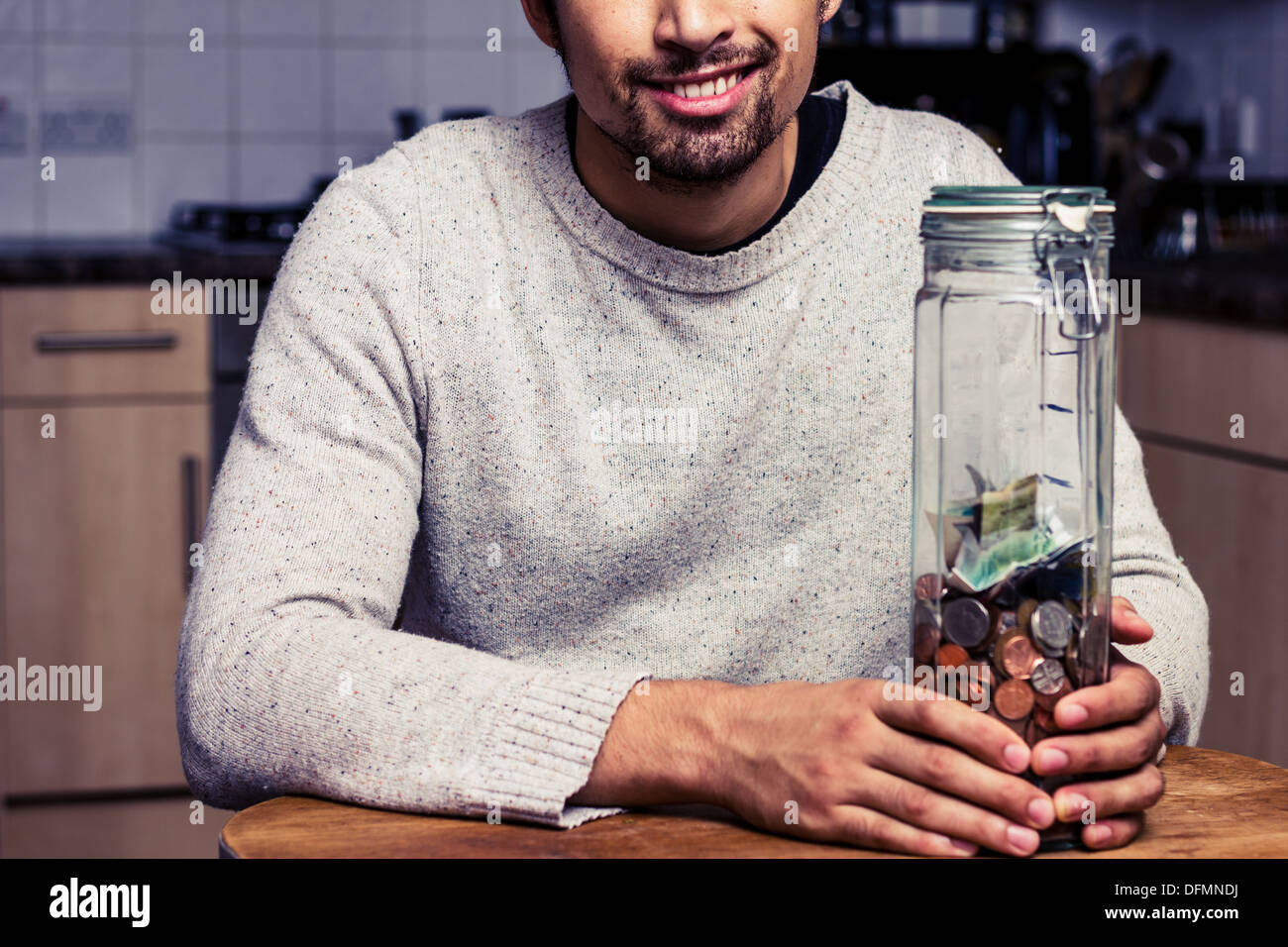 Junger Mann mit großen Glas mit Geld Stockfoto