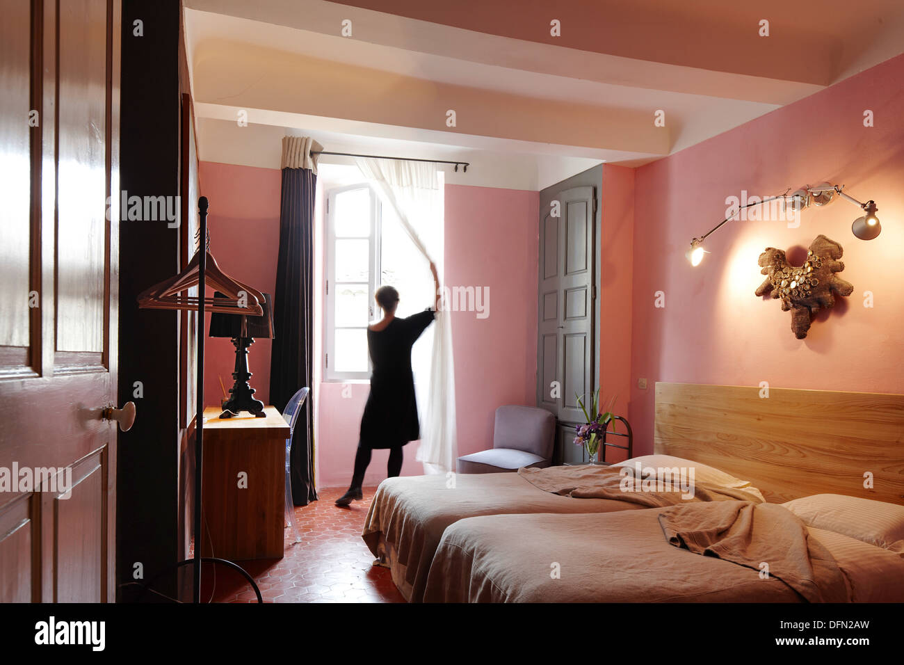 Frau öffnen Vorhänge, Schlafzimmer mit Doppelbett, B und B Chambre Avec Vue, Luberon, Frankreich Stockfoto