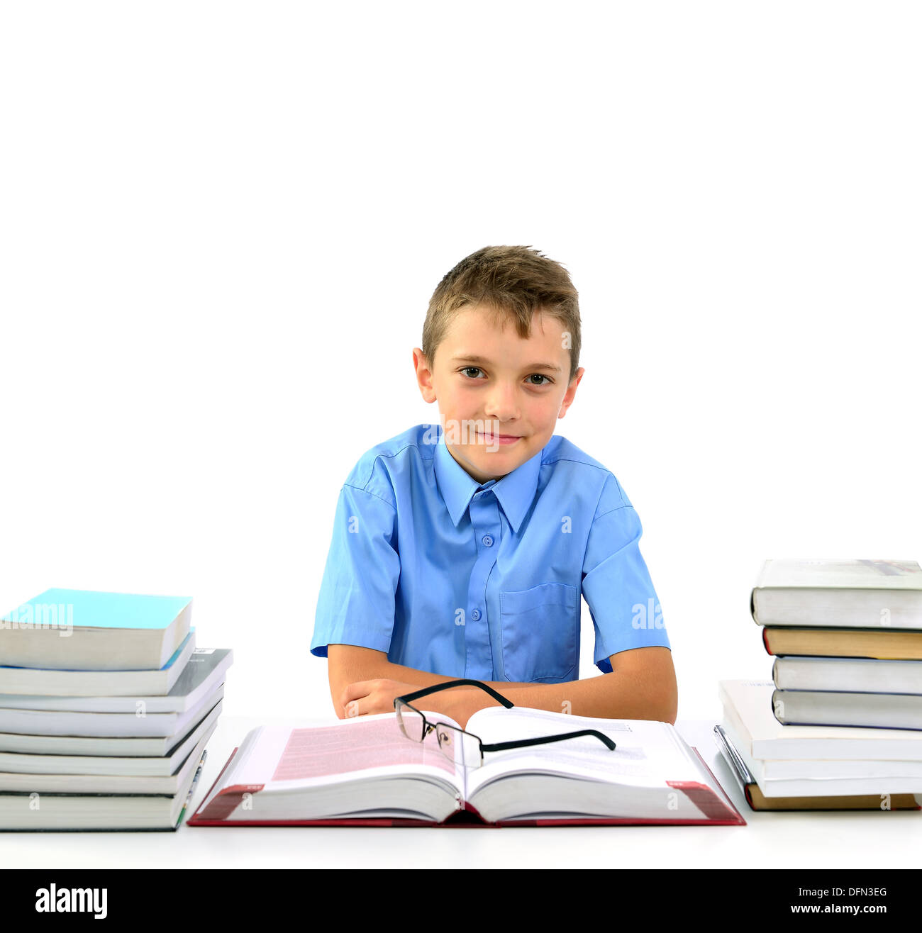 Glücklicher Junge sieht aus wie ein Geschäftsmann sitzt zwischen Büchern Stockfoto