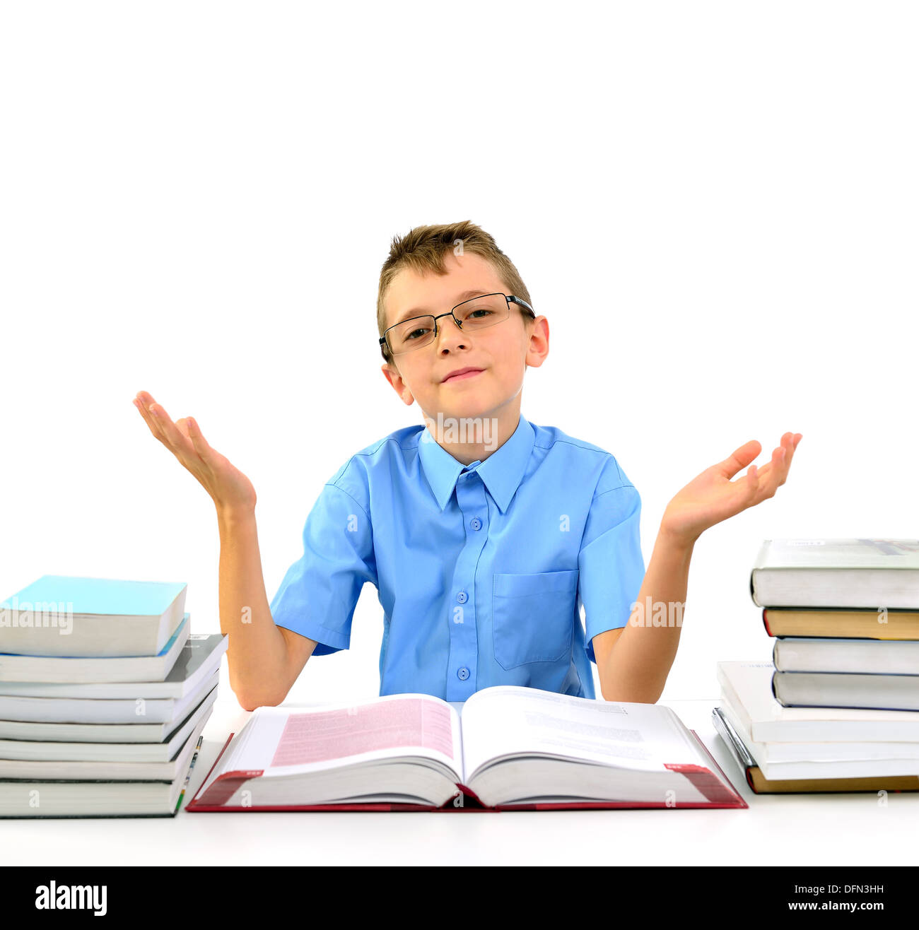 Glücklicher Junge sieht aus wie ein Geschäftsmann sitzt zwischen Büchern und zeigt offene Hände Stockfoto