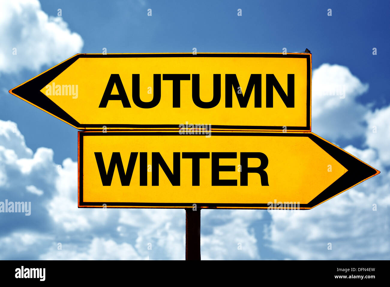 Herbst oder Winter, entgegengesetzte Vorzeichen. Zwei leere entgegengesetzte Vorzeichen vor blauem Himmelshintergrund. Stockfoto