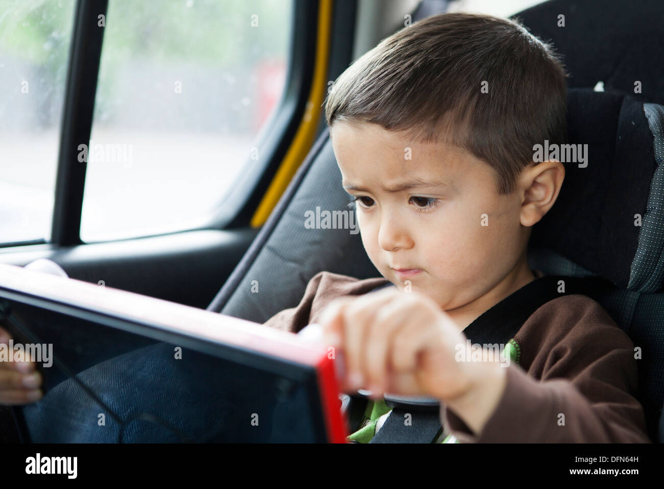 Ein japanisch-amerikanischer Junge, ein 4 jähriger Junge zieht auf seinem Ätzen und skizzieren Sie sitzend in seinem Autositz. Stockfoto