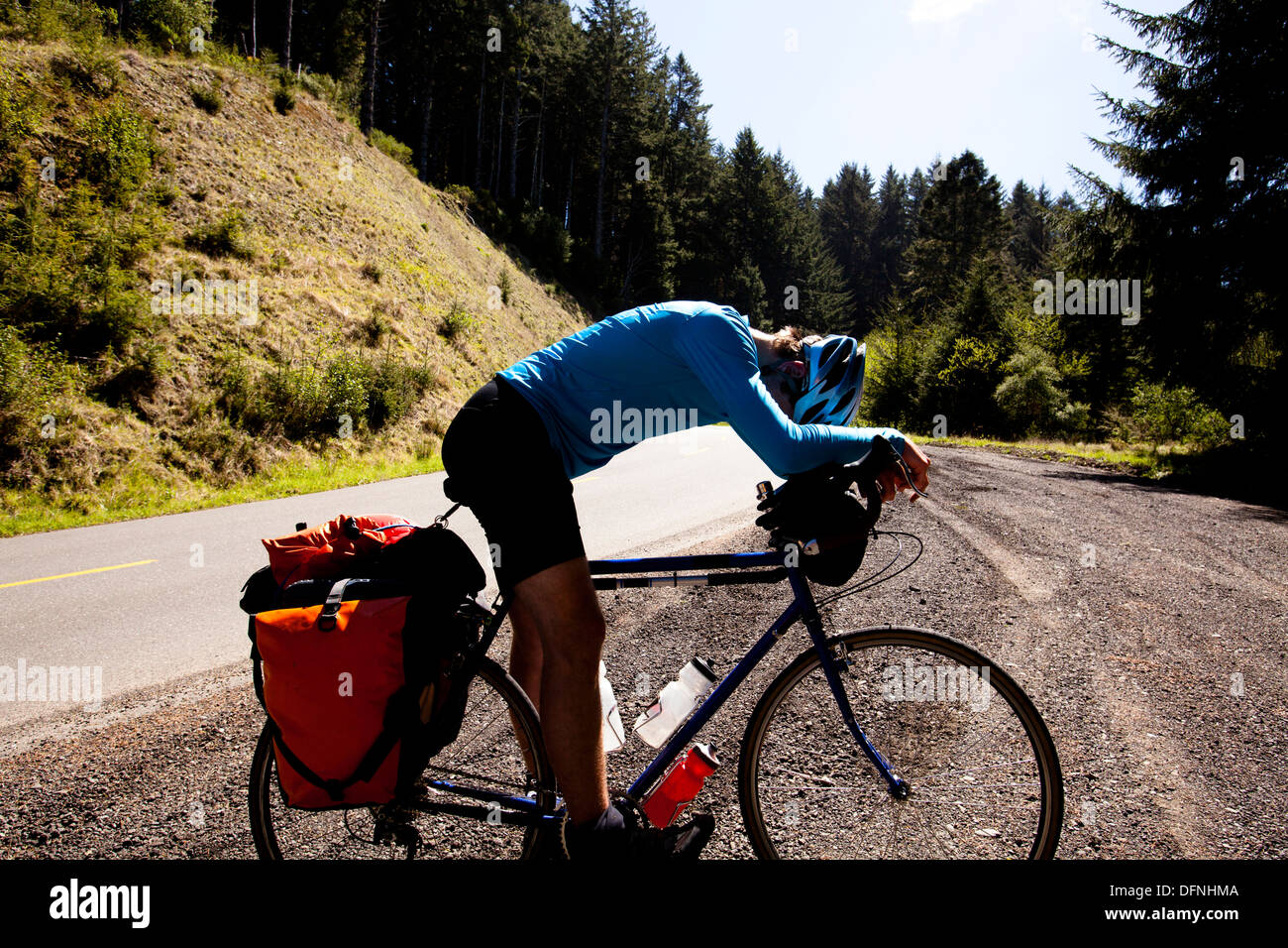 Ein erschöpfter männliche Radfahrer beugt sich über seine Tourenrad beim Klettern beginnt Road in der Nähe von Ferndale, Kalifornien. Stockfoto
