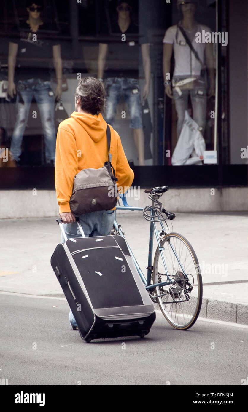 Mann zu Fuß auf der Straße mit dem Fahrrad, Koffer und Tasche, Genf, Schweiz,  Schaufenster im Hintergrund Stockfotografie - Alamy