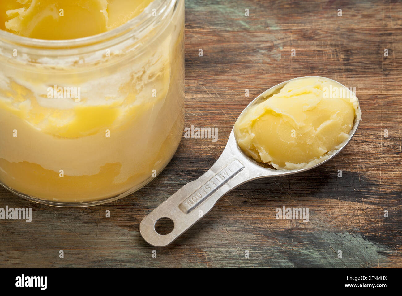 JAR und Messung Esslöffel Ghee - Butterschmalz auf Grunge Holz Stockfoto