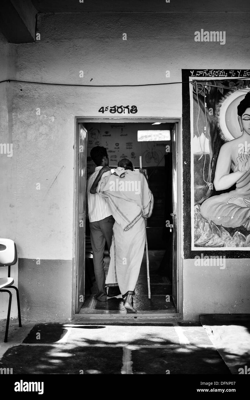 Alten indischen Sadhu in Sri Sathya Sai Baba-mobile Outreach-Klinik geholfen. Andhra Pradesh, Indien. Monochrom Stockfoto