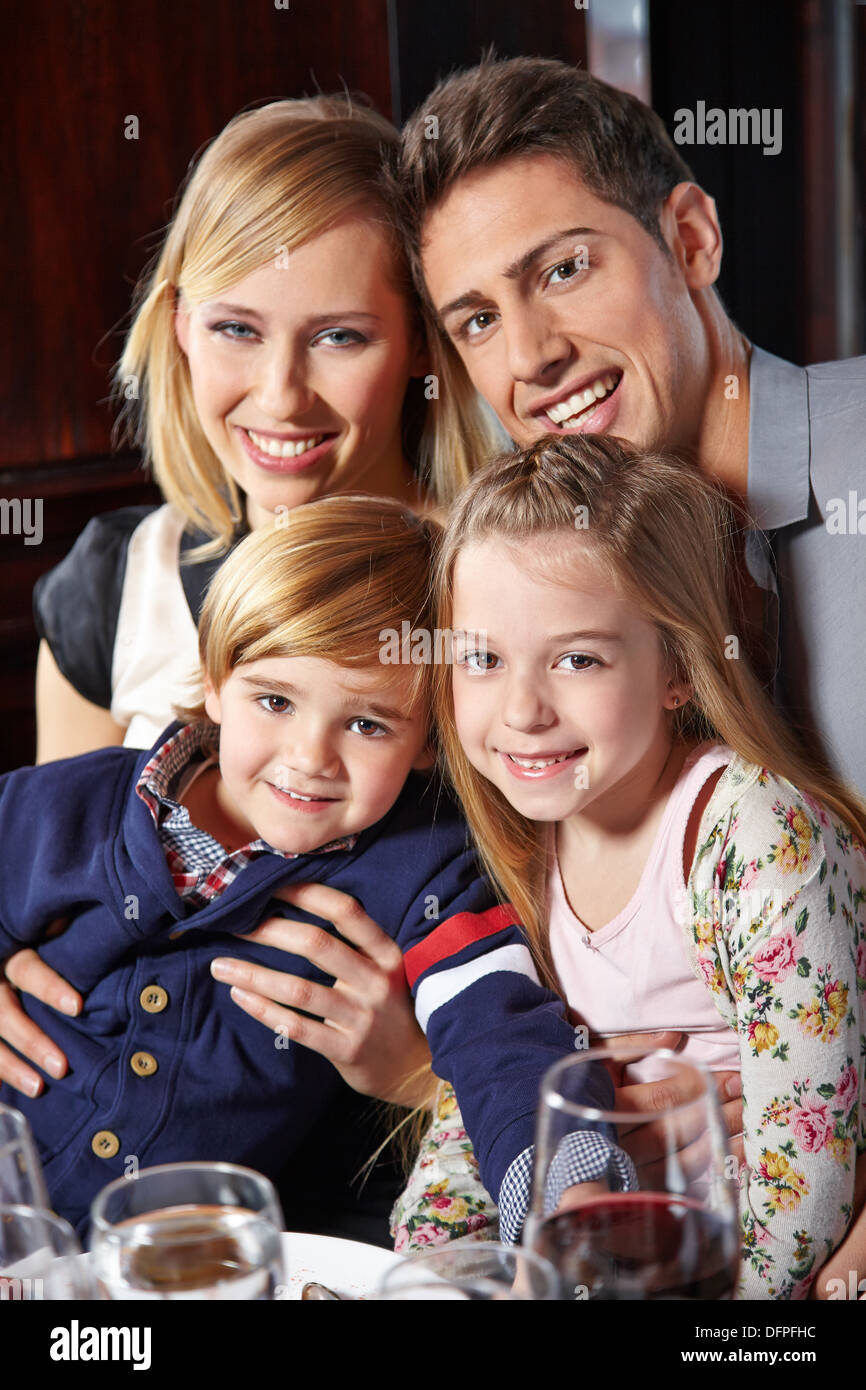 Glückliche Familie mit zwei Kindern sitzen am Esstisch Stockfoto