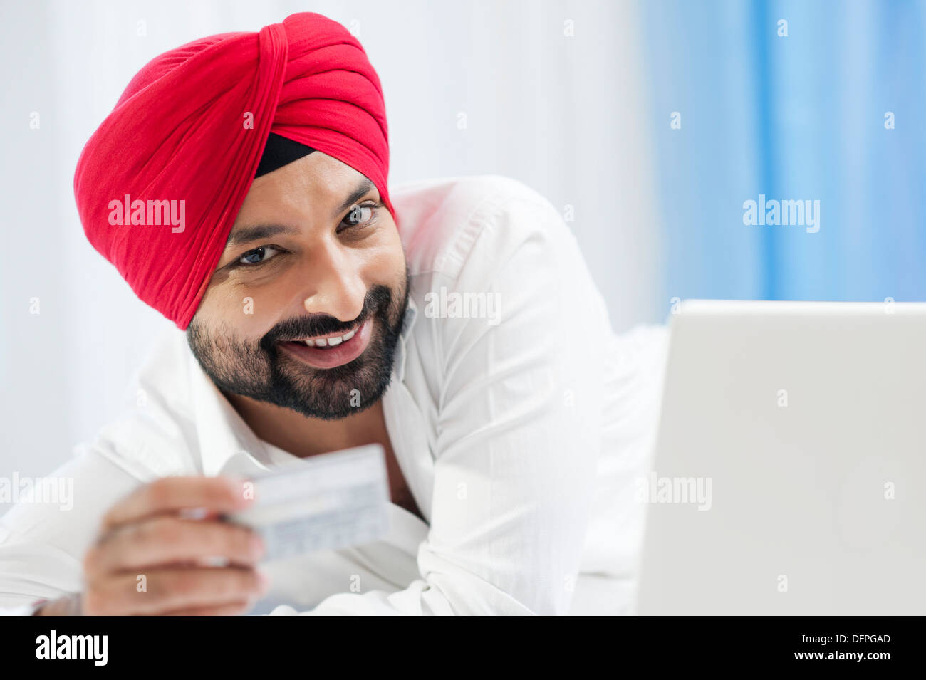 Lächeln auf den Lippen Sikh Mann tut, Online-shopping mit Kreditkarte Stockfoto