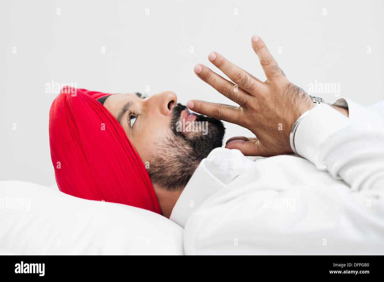 Sikh Mann auf dem Bett liegend und denken Stockfoto