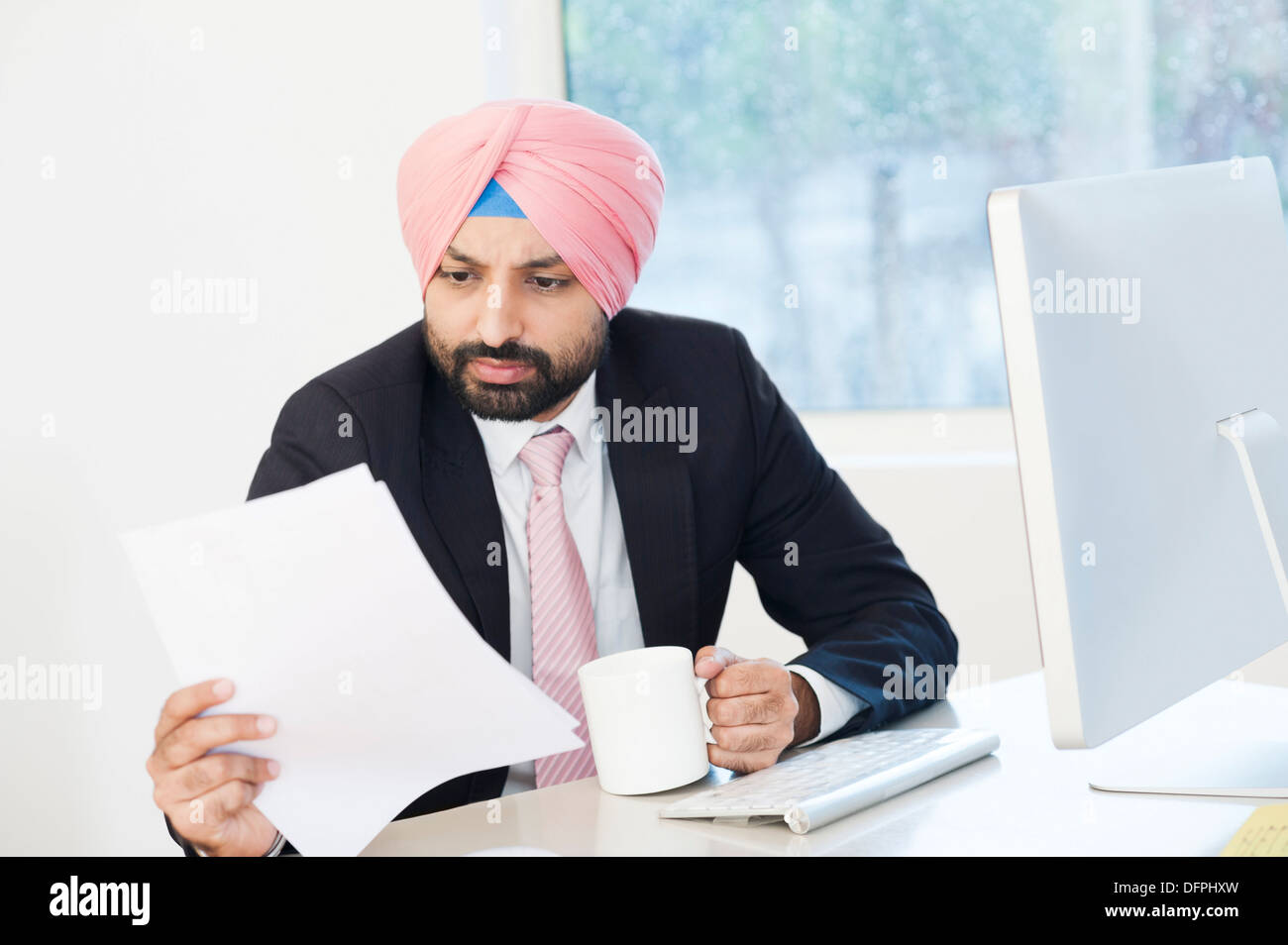 Geschäftsmann, Lesen eines Dokuments beim Kaffeetrinken in einem Büro Stockfoto