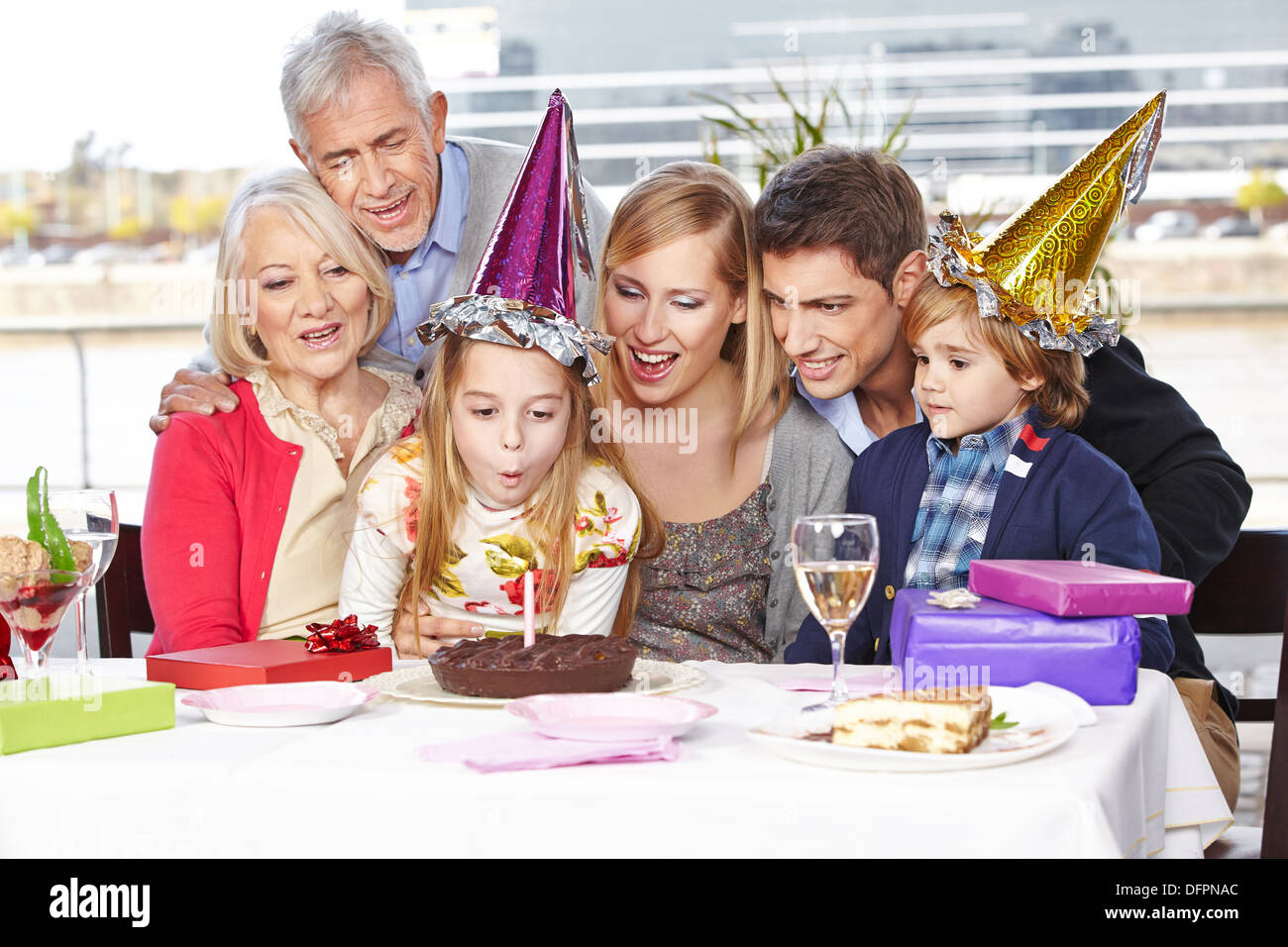 Glückliches Mädchen Ausblasen der Kerzen auf Geburtstagsparty mit ihrer Familie Stockfoto