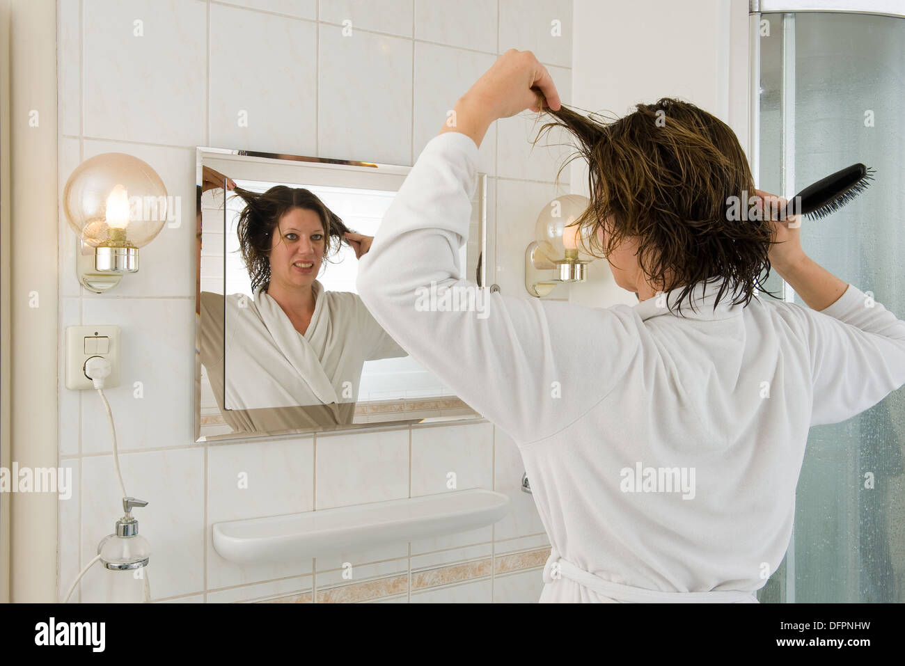 Eine Frau ist Blick in den Spiegel im Bad und ein "bad Hair Day". Stockfoto