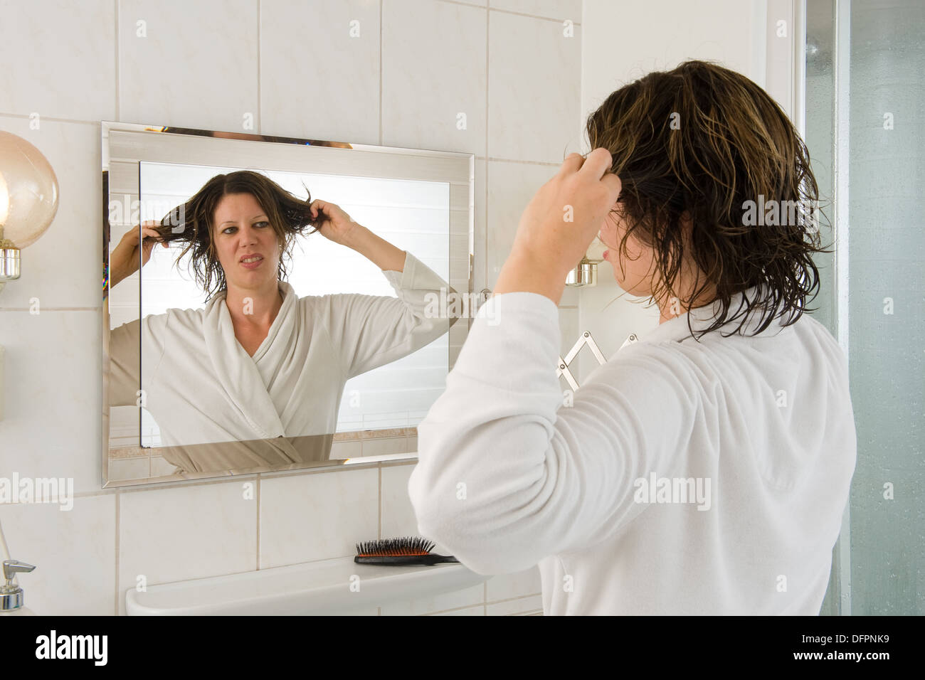 Eine Frau ist Blick in den Spiegel im Bad und ein "bad Hair Day". Stockfoto