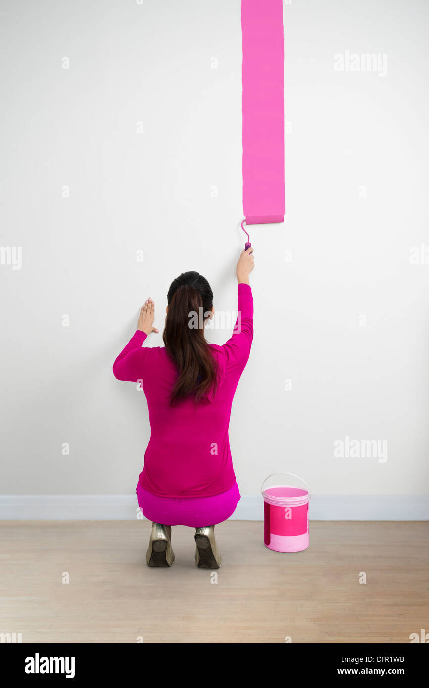 Frau malt eine Wand mit einer rosa Farbe Stockfoto