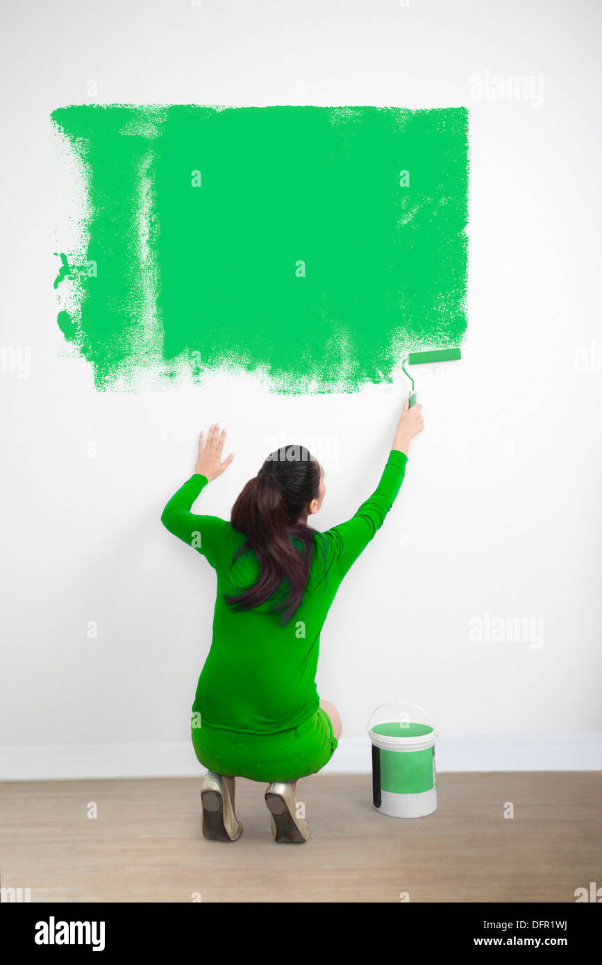 Frau malt eine Wand mit einer grünen Farbe Stockfoto