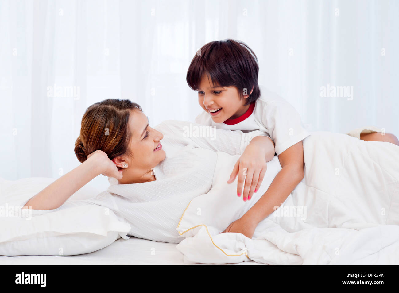 Frau und ihr Sohn auf dem Bett liegend und lächelnd Stockfoto