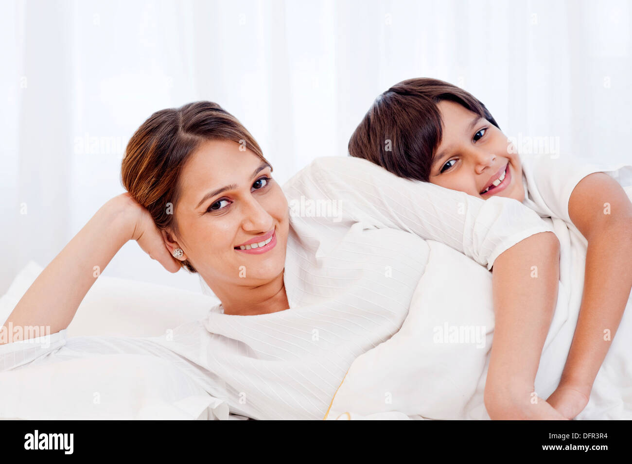 Frau und ihr Sohn auf dem Bett liegend und lächelnd Stockfoto