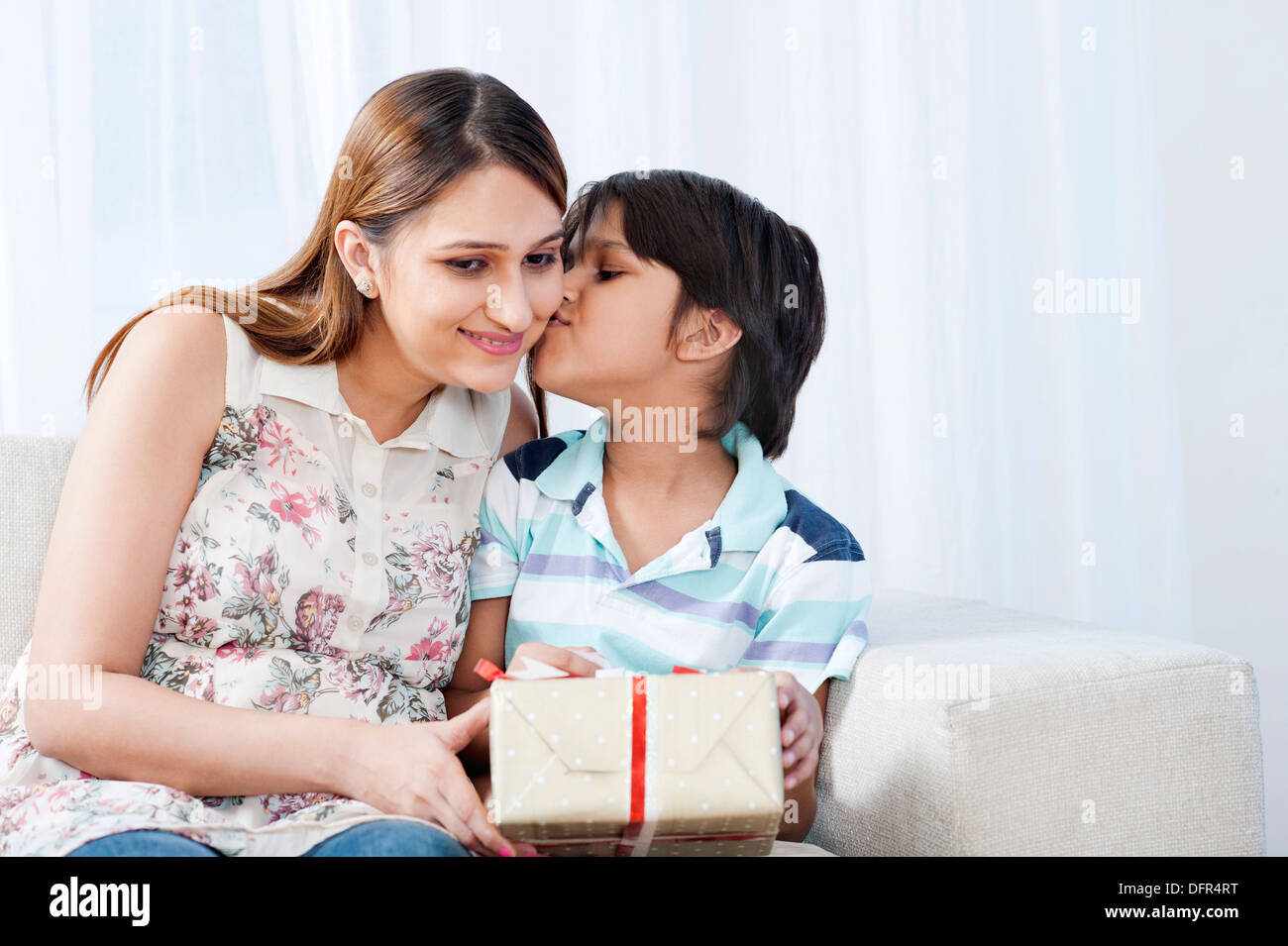 Junge küssen seine Mutter hält ein Geschenk Stockfoto