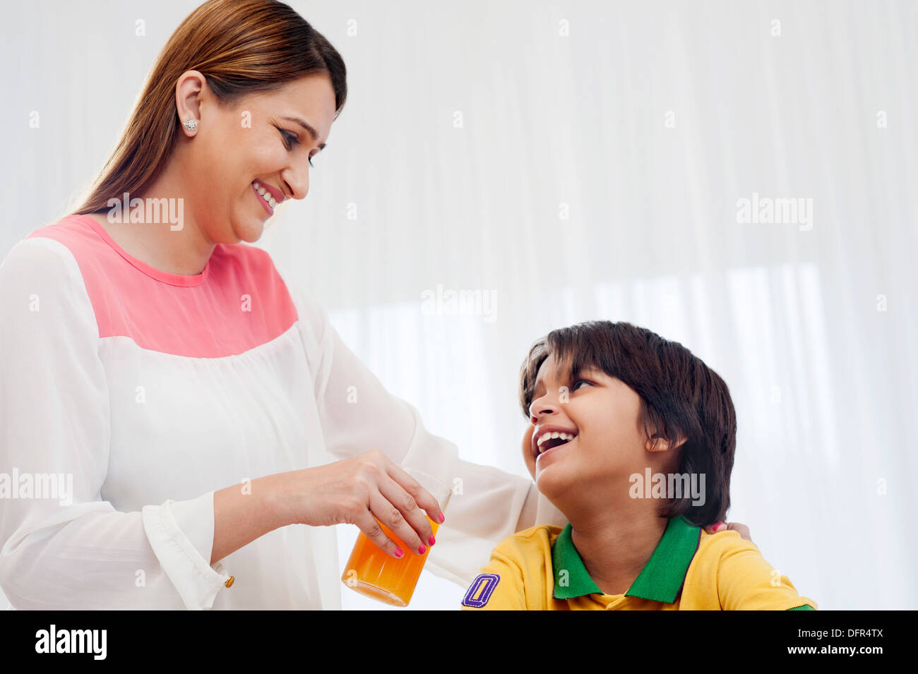 Lächelnde Frau, die Verfütterung von Saft an ihren Sohn Stockfoto