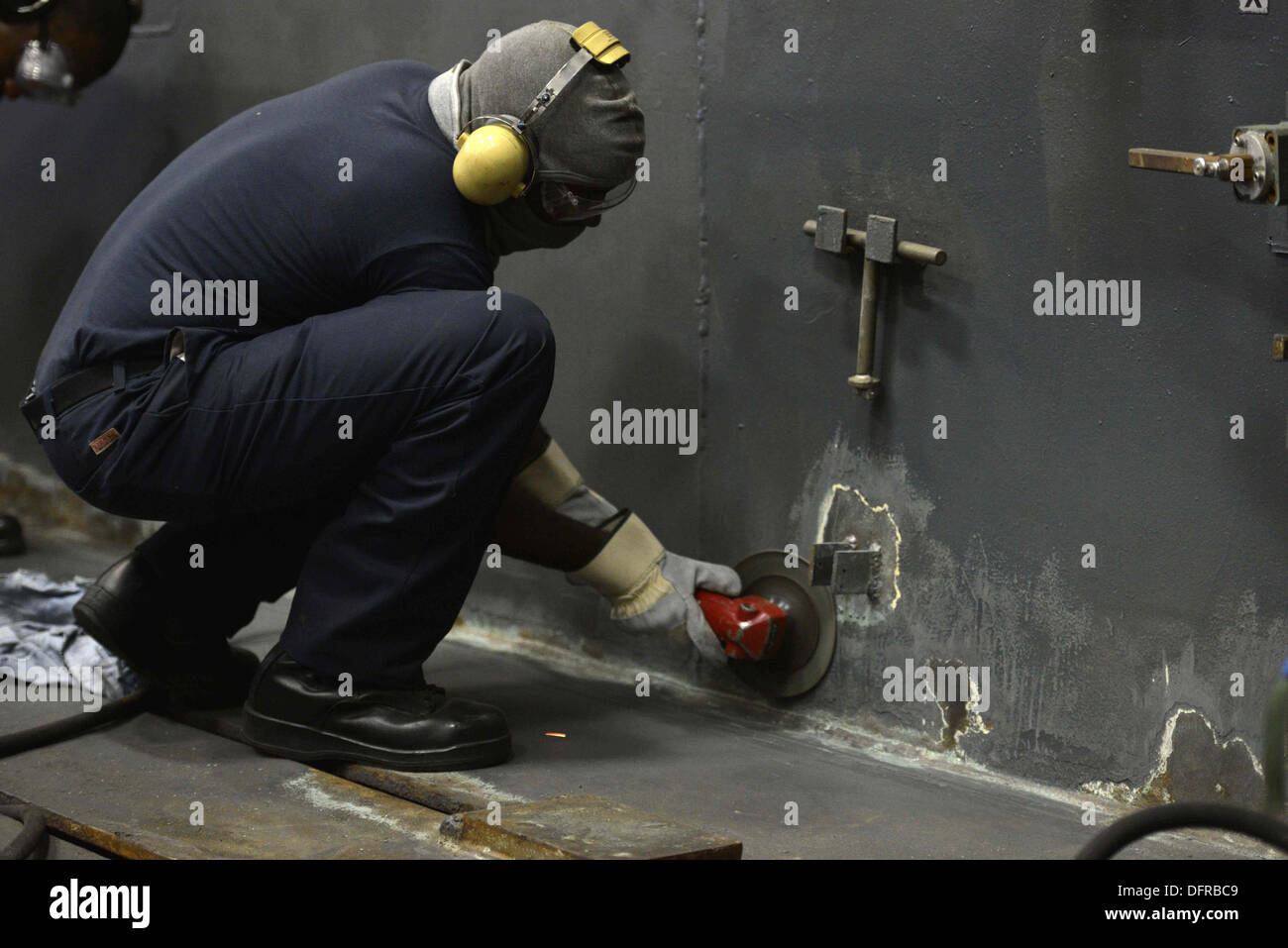 Luftfahrt Boatswain Mate (Handling) Schiff 3. Klasse Corey Collins verwendet ein abrasiver Schleifer vorzubereiten ein SCHOTT für Grundierung Okt. 3 im Hangar Bucht an Bord der Mehrzweck amphibischer Angriff USS Bataan (LHD-5). Bataan Segler und 22. Marine Ex Stockfoto