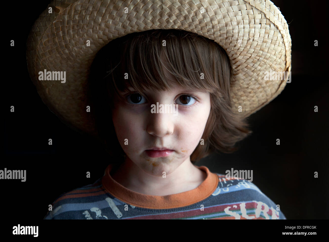 Vier und eine Hälfte Jahr alt junge trägt einen geflochtenen Hut und ernst. Stockfoto