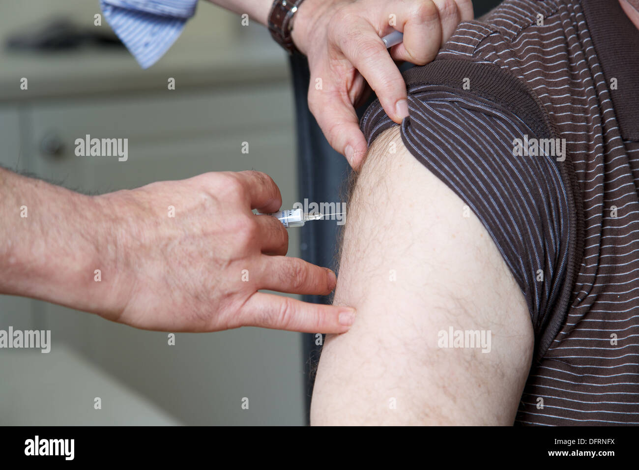 Arzt GP bereitet, die Grippe Jab Injektion zu einem Patienten Stockfoto