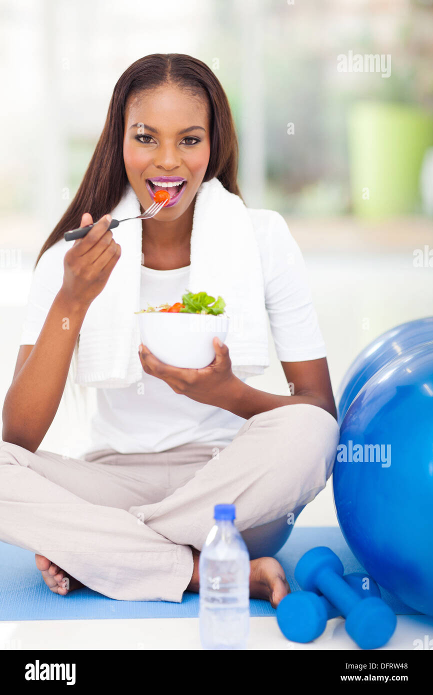 ziemlich Afro Amerikanerin essen Salat auf Gymnastikmatte Stockfoto