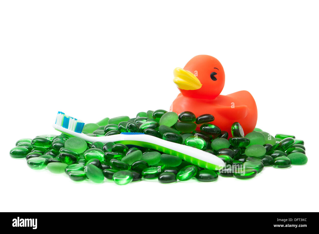 Ein Rubber Duckie und eine Zahnbürste auf einem Meer von grünen Glasperlen, isoliert auf weiss schafft ein sauberes Bild, das Kinder-Badezimmer sagt. Stockfoto