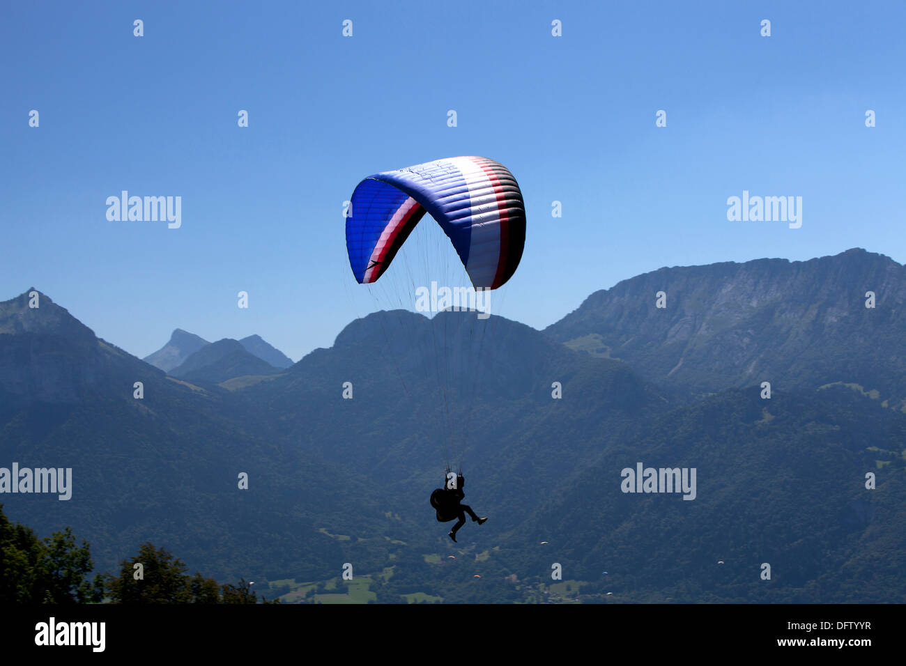 Ein Gleitschirm im Flug über ein Alpental in der Haute Savoie Region in der Nähe von Annecy, Frankreich Stockfoto