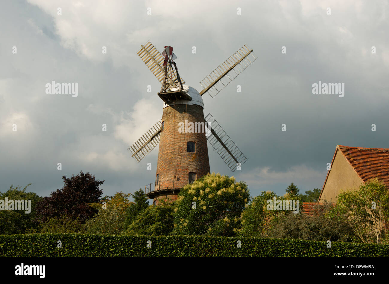 Quainton Windmühle, segelt eine renovierte Windmühle mit Mütze und Fantail gegen einen stürmischen Himmel. Stockfoto