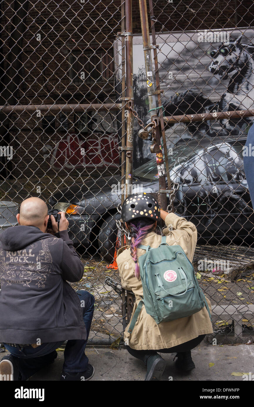 New York City, NY, USA. 9. Oktober 2013. Graffiti-Fans strömen in ein unbebautes Grundstück im Stadtteil Lower East Side von New York auf Mittwoch, 9. Oktober 2013, die neunte Ausgabe von Banksy-Graffiti-Kunst zu sehen. Diese besondere Ausgabe wird durch einen Maschendrahtzaun und einen verschlossenen Zaun angesehen. © Richard Le Credit: Richard Levine/Alamy Live-Nachrichten Stockfoto