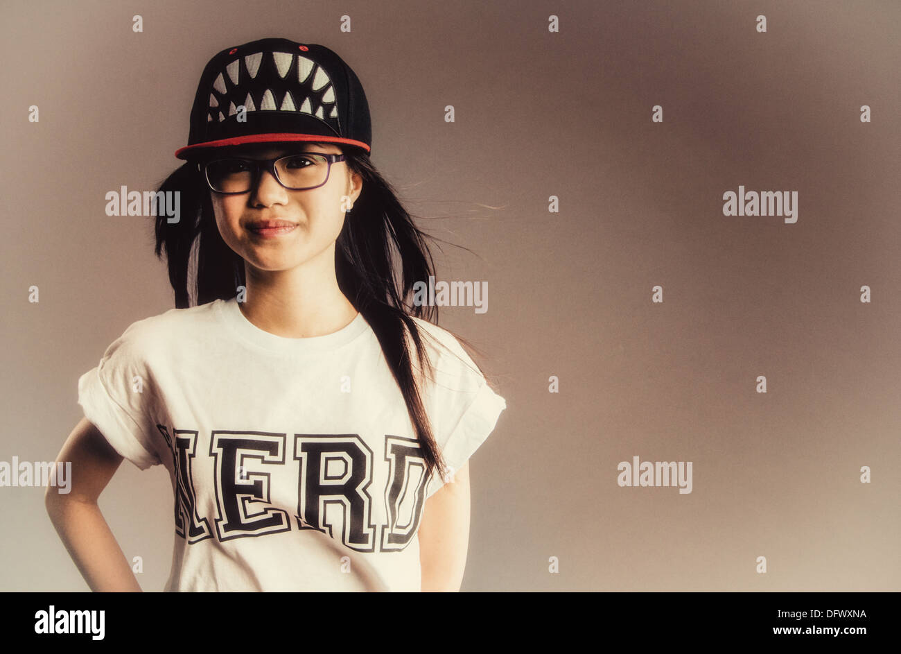 Eine asiatische Mädchen in einem Nerd T-shirt und eine Baseball-Cap mit Zähnen auf Stockfoto