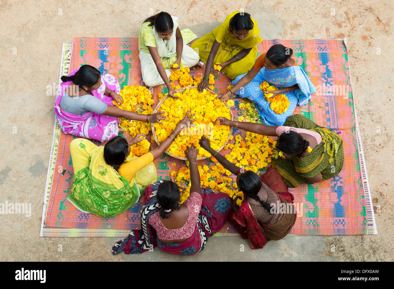 Ländliche Indianerdorf Frauen sitzen rund um einen Korb mit Ringelblumen machen Blumengirlanden. Andhra Pradesh, Indien Stockfoto