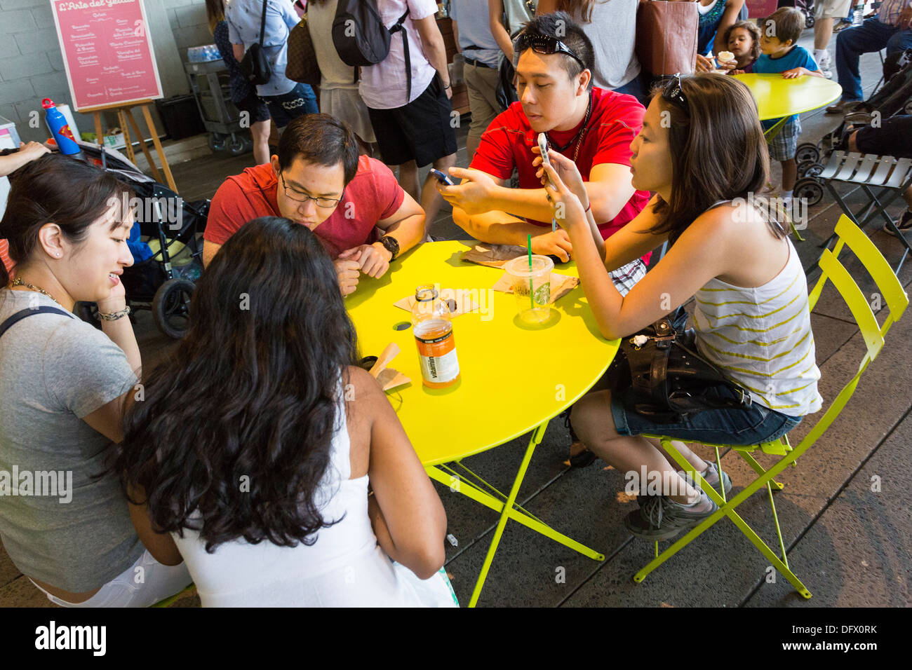 Gruppe von asiatische Teenager am runden Tisch sitzen und mit einer Mittagspause / Blick auf ihren Handys Stockfoto