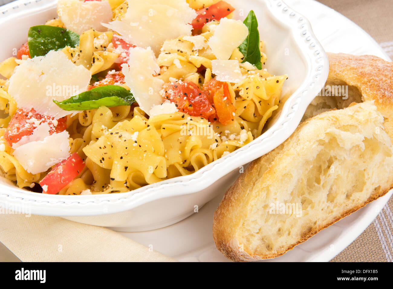 Teller mit italienischen Eiernudeln mit Tomaten, Basilikum, Pfeffer, Parmigiano-Reggiano-Käse und Olivenöl mit knusprigem Brot Stockfoto