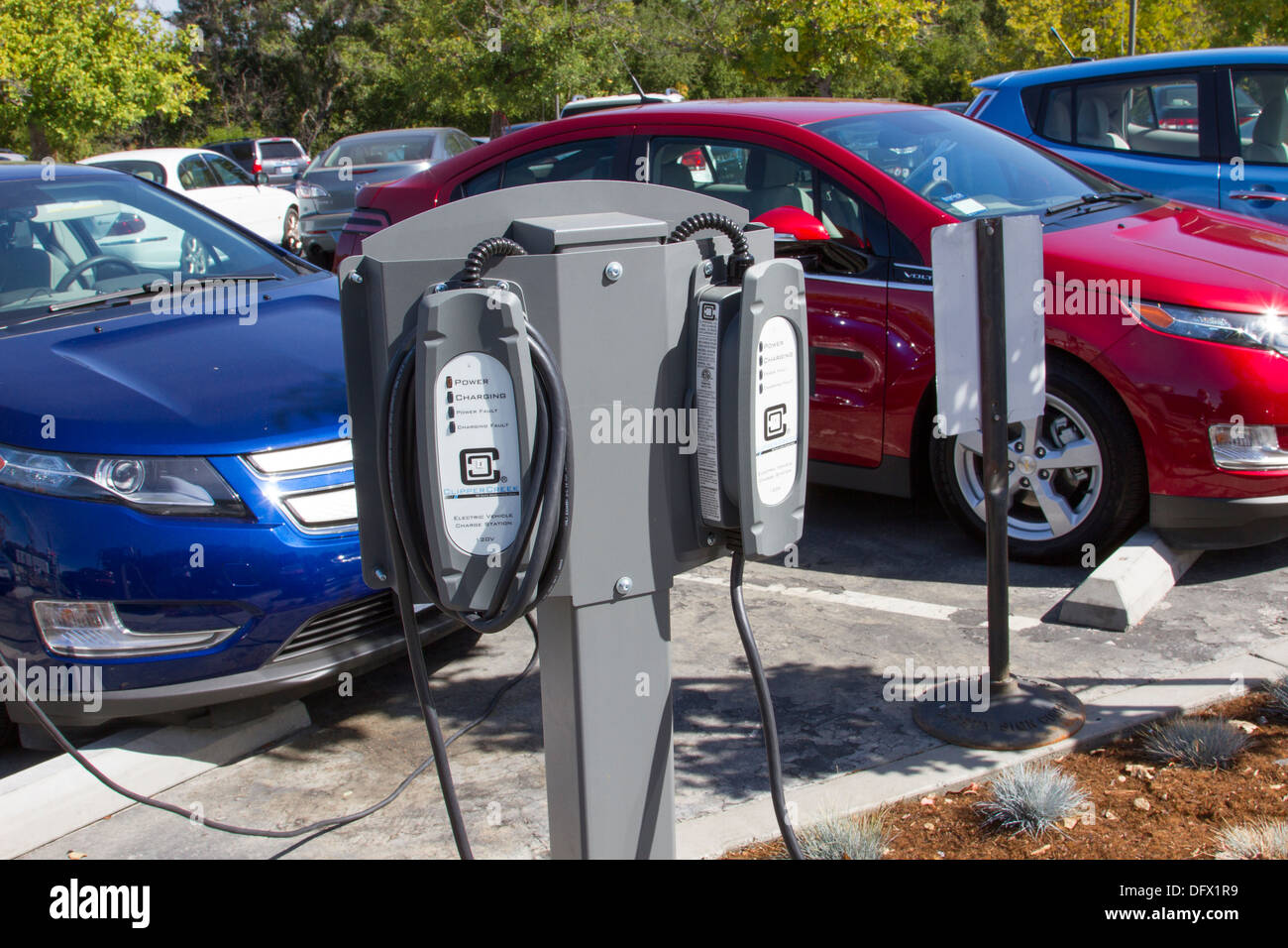 EV-Ladestationen mit Plug-in Elektroautos angeschlossen und laden ihre Batterien auf einem Parkplatz am Arbeitsplatz Stockfoto