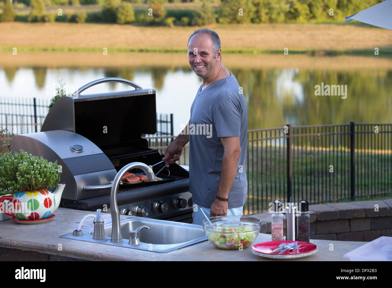 Mittleren Alter Mann Kochen Lachse am Außenküche Grill Stockfoto